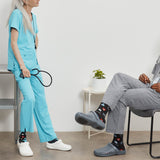 Person in light blue scrubs with a stethoscope, standing next to another person in gray pants and black Crocs.