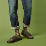 Person wearing blue jeans, sandals, and patterned beer and pizza slice socks on a green background