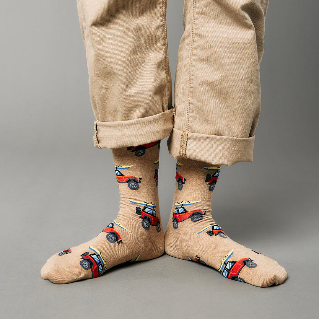 Beige socks with car pattern worn with beige pants on a gray background