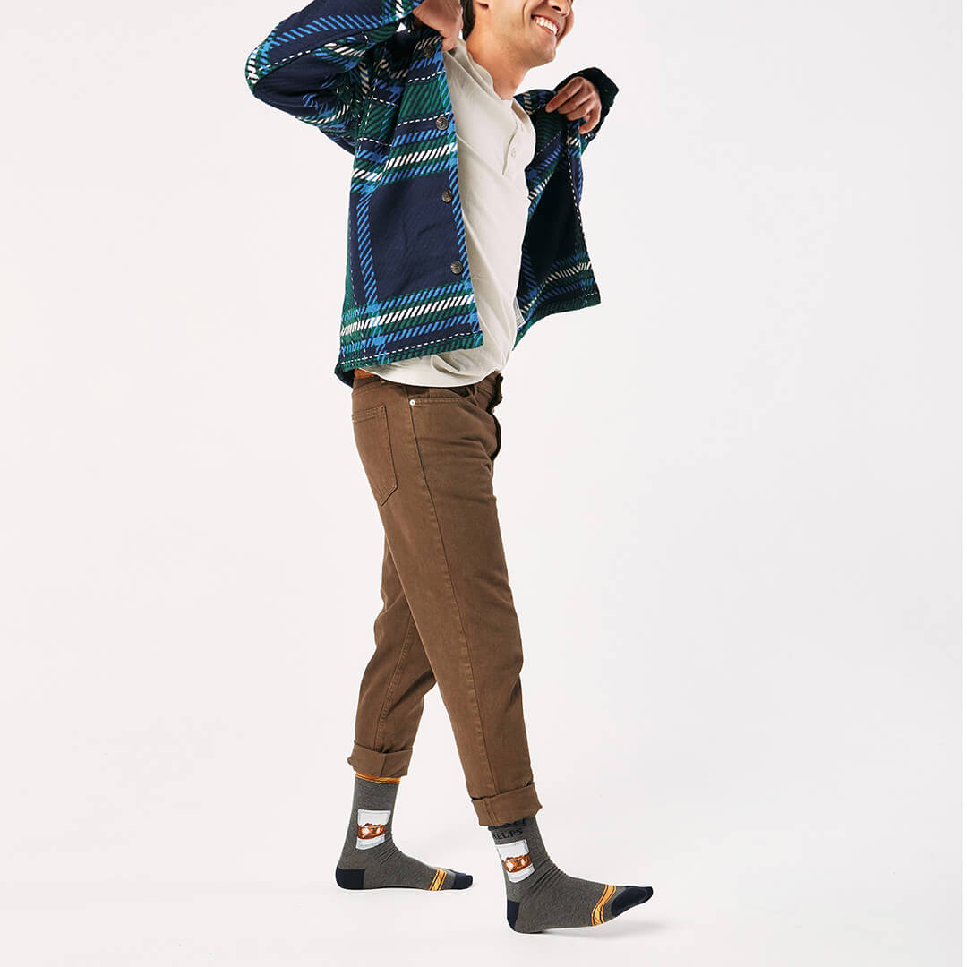 Person wearing a blue plaid jacket, brown pants, and gray socks with a whiskey glass graphic and text that says "Whiskey Helps"  on a white background