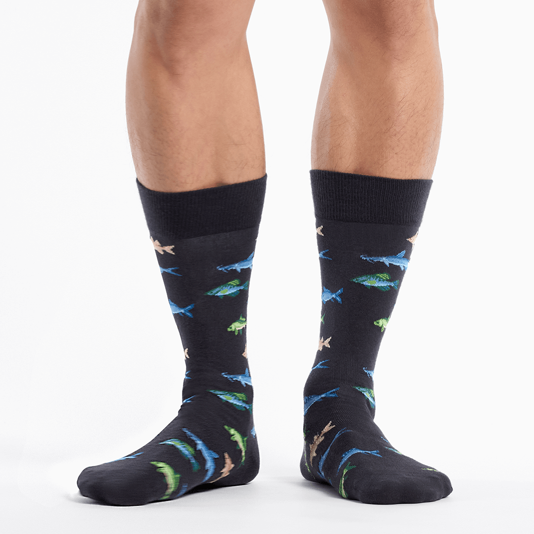 Black socks with colorful fish pattern worn by a person on a white background