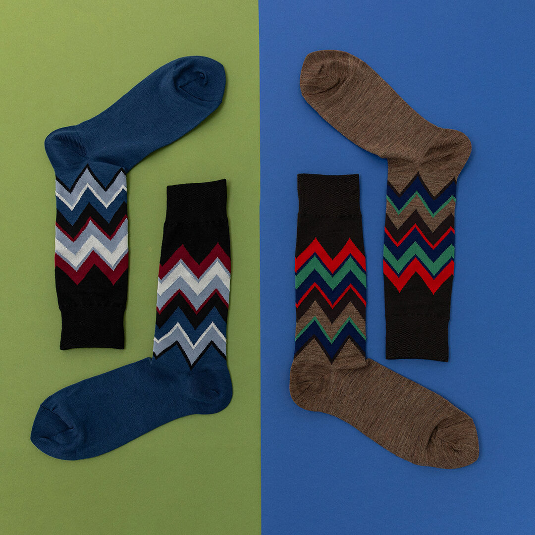 Two pairs of socks with zigzag chevron patterns on a green and blue background