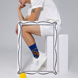 Person wearing blue socks with 'The Dinker' design and white sneakers on a light gray background