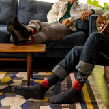 Two people sitting on a couch with one wearing socks featuring dice designs.