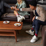Three people sitting on a couch with a coffee table in front of them, enjoying snacks and drinks. thumbnail