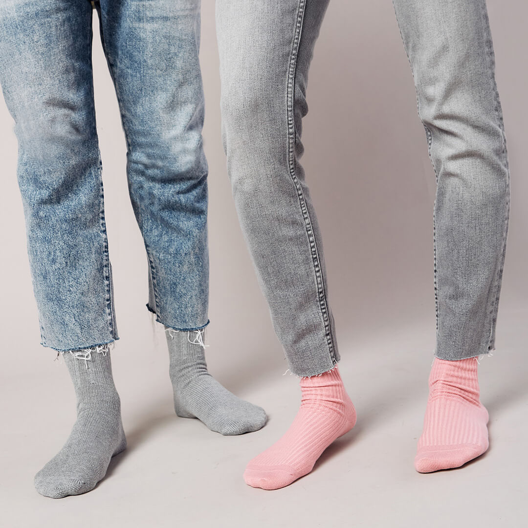 Two pairs of jeans worn by different people on a plain background