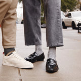 Two pairs of feet wearing different shoes on a sidewalk. thumbnail