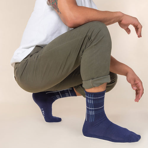 Person wearing green pants and blue plaid socks on a beige background