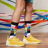 Person wearing colorful socks with a pattern and yellow sneakers on a wooden floor. thumbnail