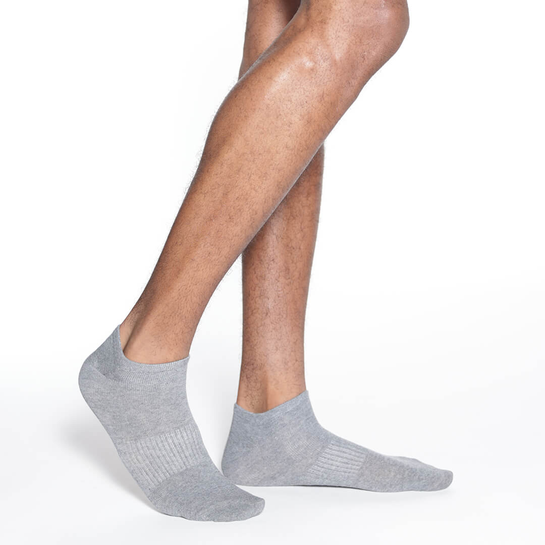 Gray ankle socks worn by a person on a white background