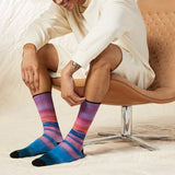 Person wearing colorful striped socks sitting on a chair.