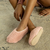 Person wearing pink fuzzy slippers on a carpeted floor thumbnail
