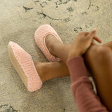 Person wearing pink fuzzy slippers on a textured surface thumbnail