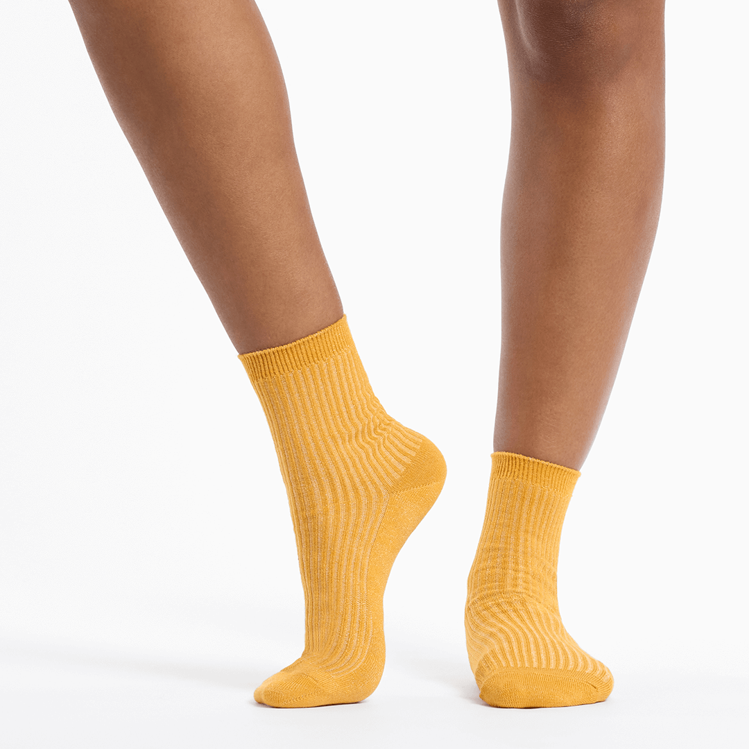 Metallic gold socks worn by a person on a white background