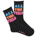 A pair of black fuzzy socks with the text 'All The Feels' in blue and pink colors, and the brand name 'K.Bell' at the end of the foot.