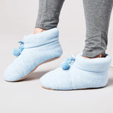 Light blue slip-on shoes with pom-poms worn by a person in gray pants on a light background thumbnail