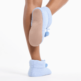 Light blue slippers with pom-poms worn by a person on a white background thumbnail