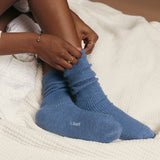 Person wearing blue socks with 'k. bell' branding on a white textured surface thumbnail