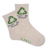A pair of white crew socks with green recycling symbols and the text 'DON'T BE TRASHY' printed on the side, signed by 'K.BELL'.