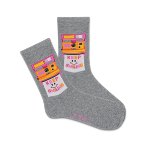 A pair of gray crew socks with a vintage camera design and the text 'KEEP SMILING' in a colorful background.