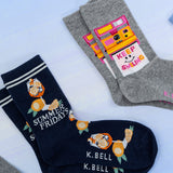 Two pairs of socks with designs and text on a light background thumbnail