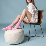 Woman sitting on a chair with pink sheer slouch socks on a light blue background thumbnail