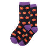 Child wearing glow-in-the-dark black socks with orange pumpkin patterns on a light wooden floor.