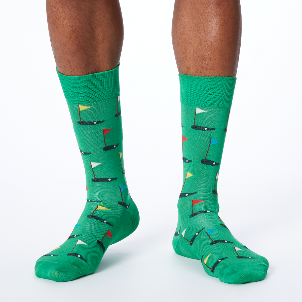 A pair of green crew socks with a pattern of golf flags.